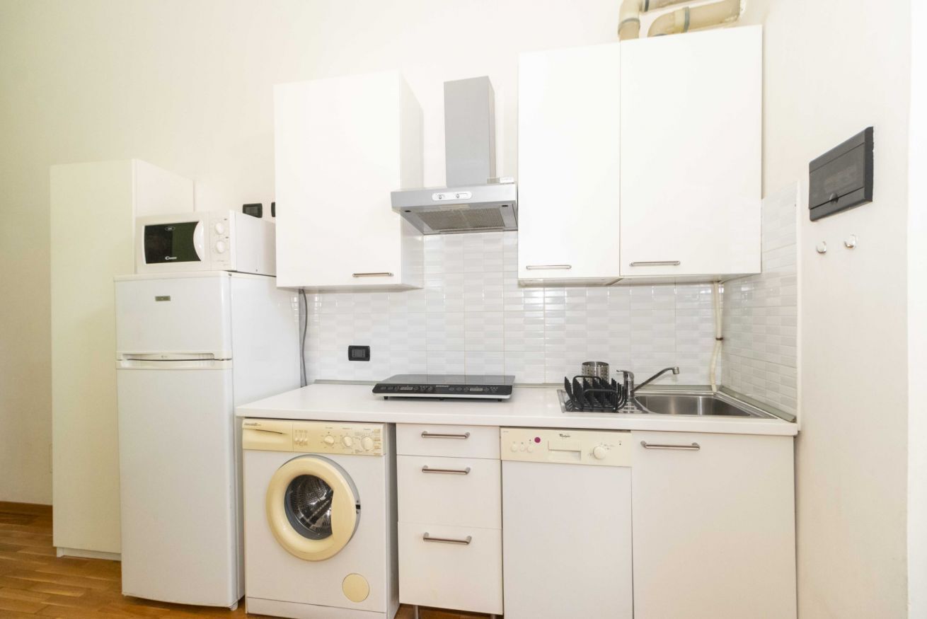 A compact kitchen with a washing machine, a microwave, and a dishwasher.