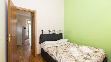 Ein Schlafzimmer mit einem Bett, einer Tür zu einem Flur und einer grünen Wand.