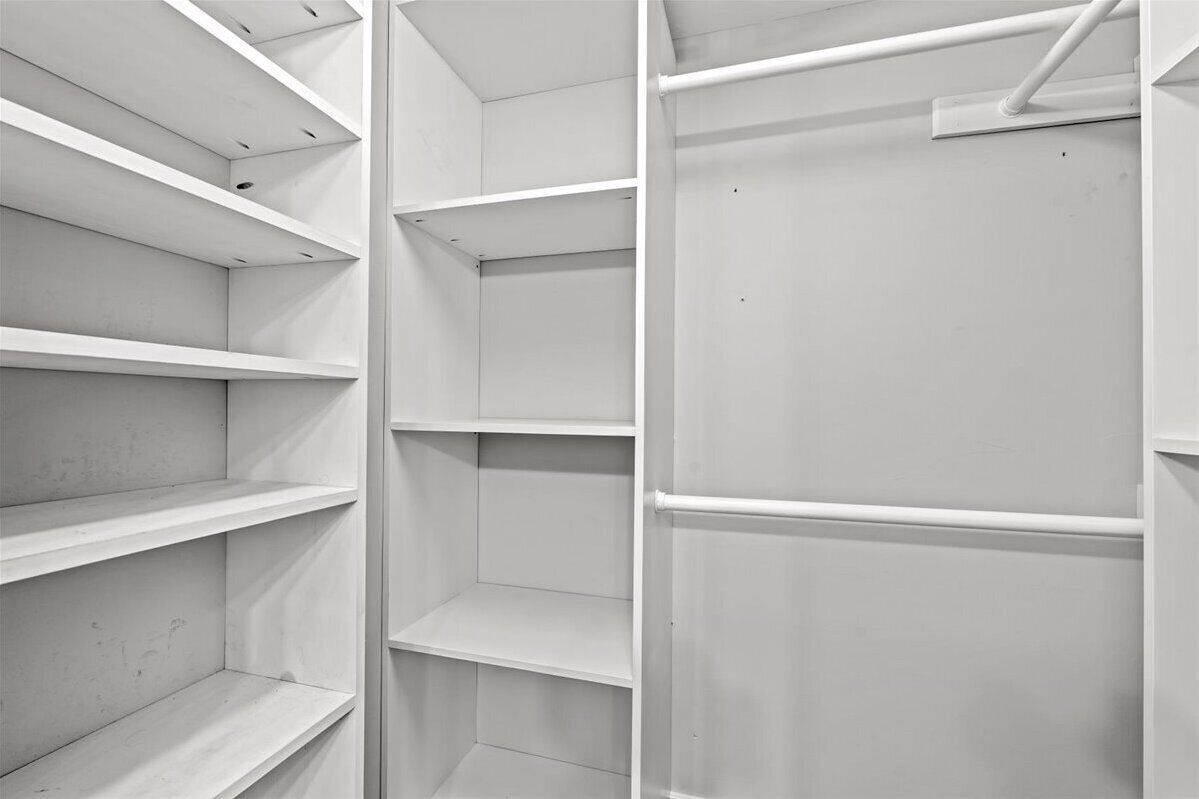 Un espace de rangement blanc et vide, doté de plusieurs étagères et d’une porte.