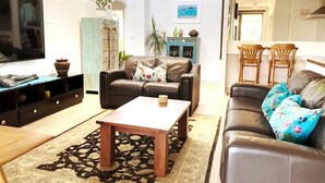 A living room with a sofa set, a coffee table, a TV, and a dining area with chairs. - Sea breeze Villa/walk everywhere/sunsets (Fremantle)