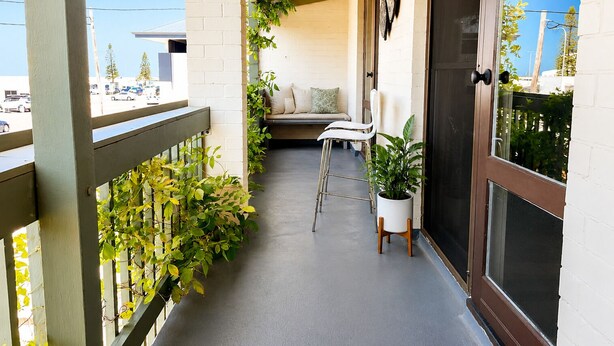 A balcony with a seating area, a potted plant, and a door. - Sea breeze Villa/walk everywhere/sunsets (Fremantle)