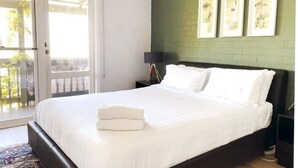 A neatly made bed with white linens, a green accent wall, and framed artwork above it. - Sea breeze Villa/walk everywhere/sunsets (Fremantle)