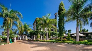 Un hotel con un patio empedrado, palmeras y un edificio con entrada visible.