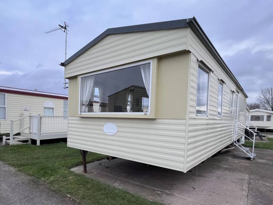 Ett hus på hjul med ett stort fönster, en liten veranda och en satellantenn.