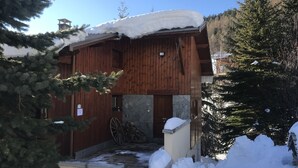 A wooden cabin with a stone foundation, a wooden door, and a chimney.