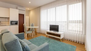 Una sala moderna con sofá, mueble para televisión y comedor.