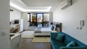 Un dormitorio moderno con una cama, un sofá azul, un escritorio y un ventanal con vistas a la ciudad.