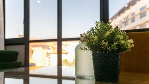Una planta en maceta sobre una mesa de vidrio, con vista a un edificio a través de grandes ventanales.