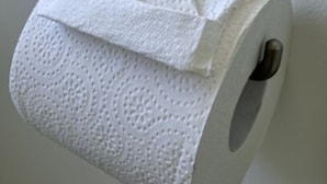 Un rollo de papel higiénico sujeto a la pared con un portaobjetos metálico.