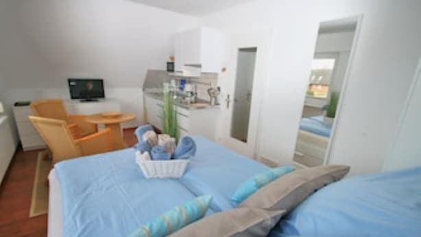 Una habitación de hotel con cama, escritorio, silla y kitchenette.