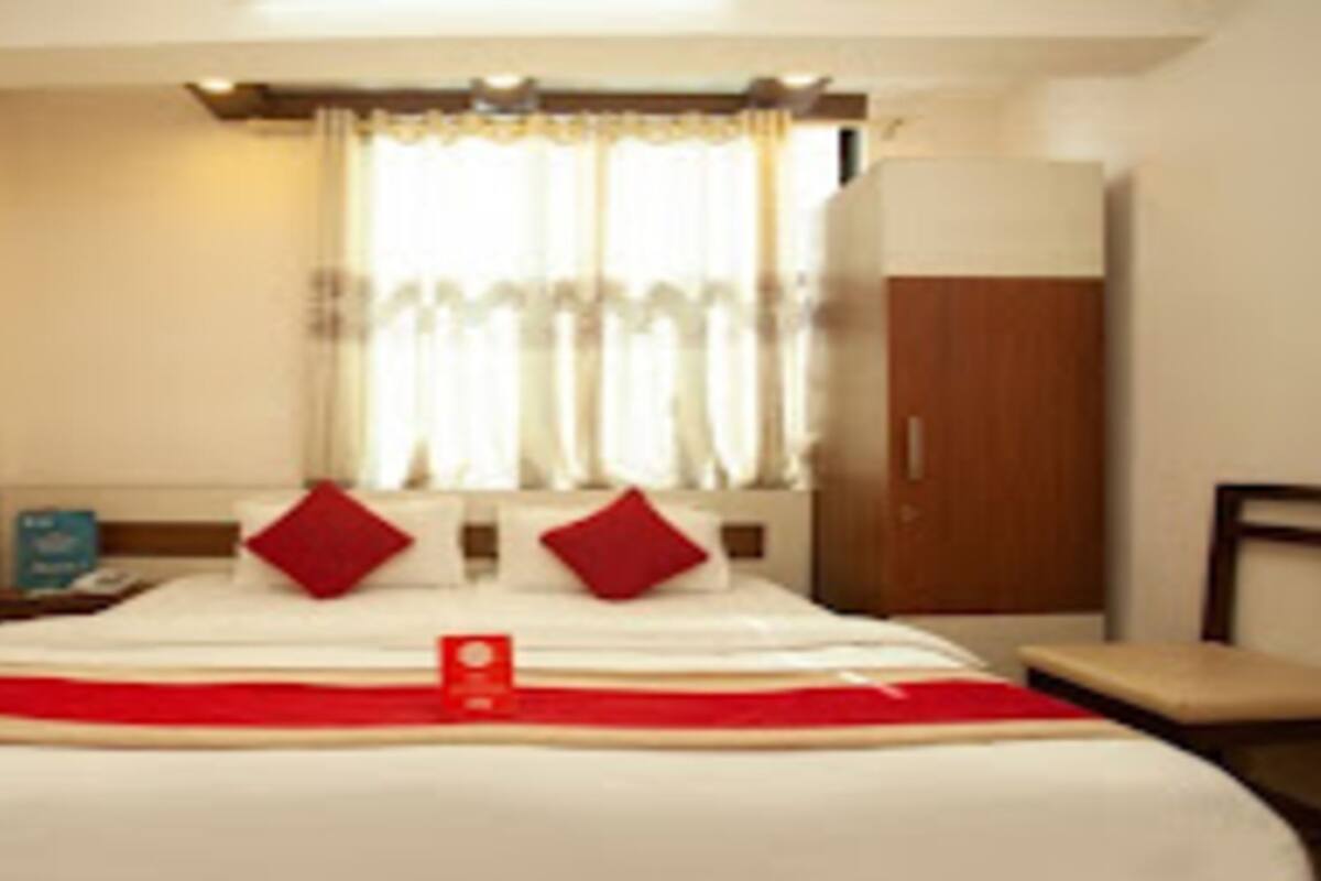 Una habitación de hotel con una cama, una mesita de noche, una silla y un armario.