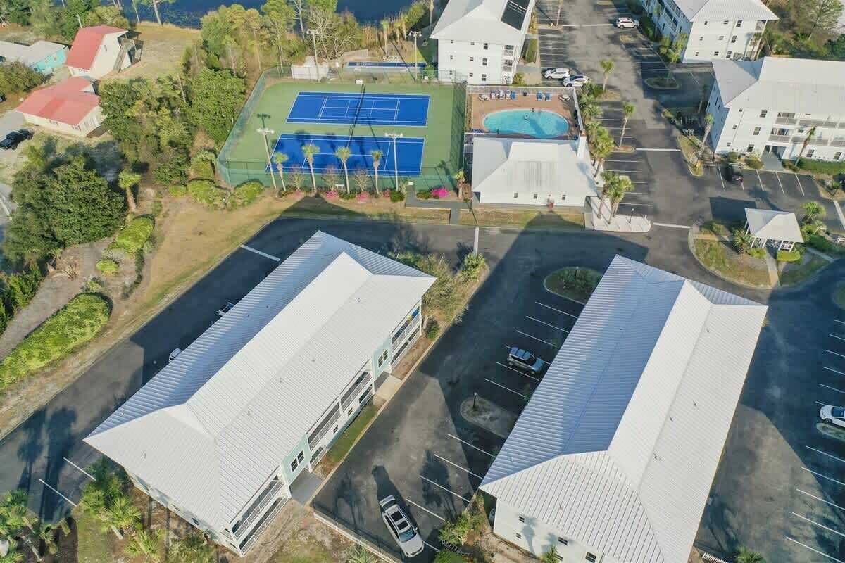 Vue aérienne d’un quartier résidentiel avec deux grands immeubles, un court de tennis et une piscine.