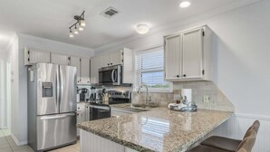 A modern kitchen with stainless steel appliances, a granite countertop, and white cabinetry. - Newly Renovated-Community Pool and Tennis Courts (Santa Rosa Beach)