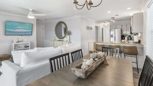 A modern living room with a white sofa, dining table, and a kitchen area in the background. - Newly Renovated-Community Pool and Tennis Courts (Santa Rosa Beach)