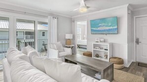 A modern living room with a white sofa, a coffee table, and a TV mounted on the wall. - Newly Renovated-Community Pool and Tennis Courts (Santa Rosa Beach)