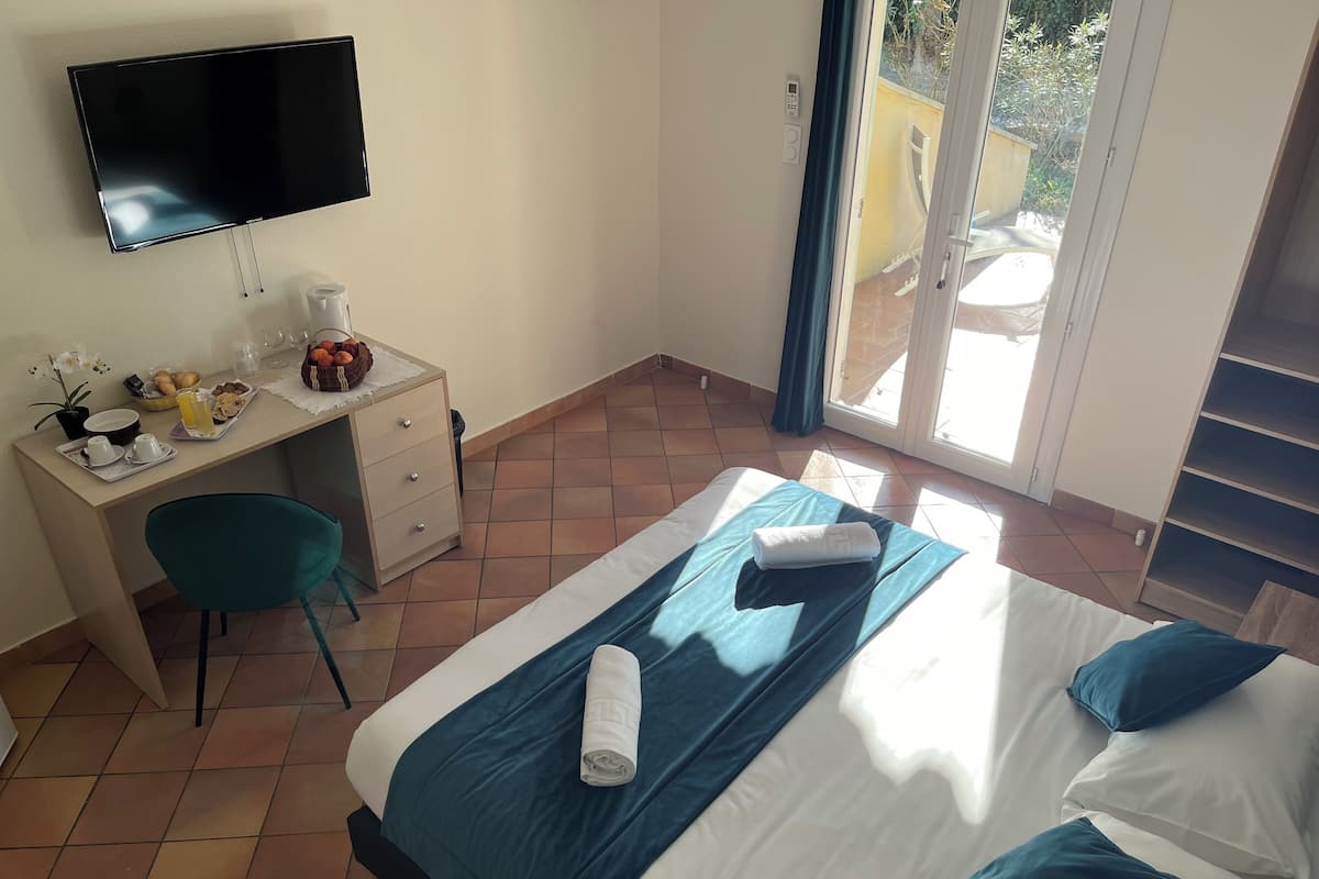 A hotel room with a bed, a desk, a chair, a TV, and a balcony.