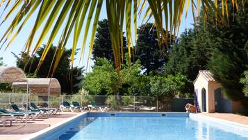 Una piscina con sillas de descanso y palmeras.