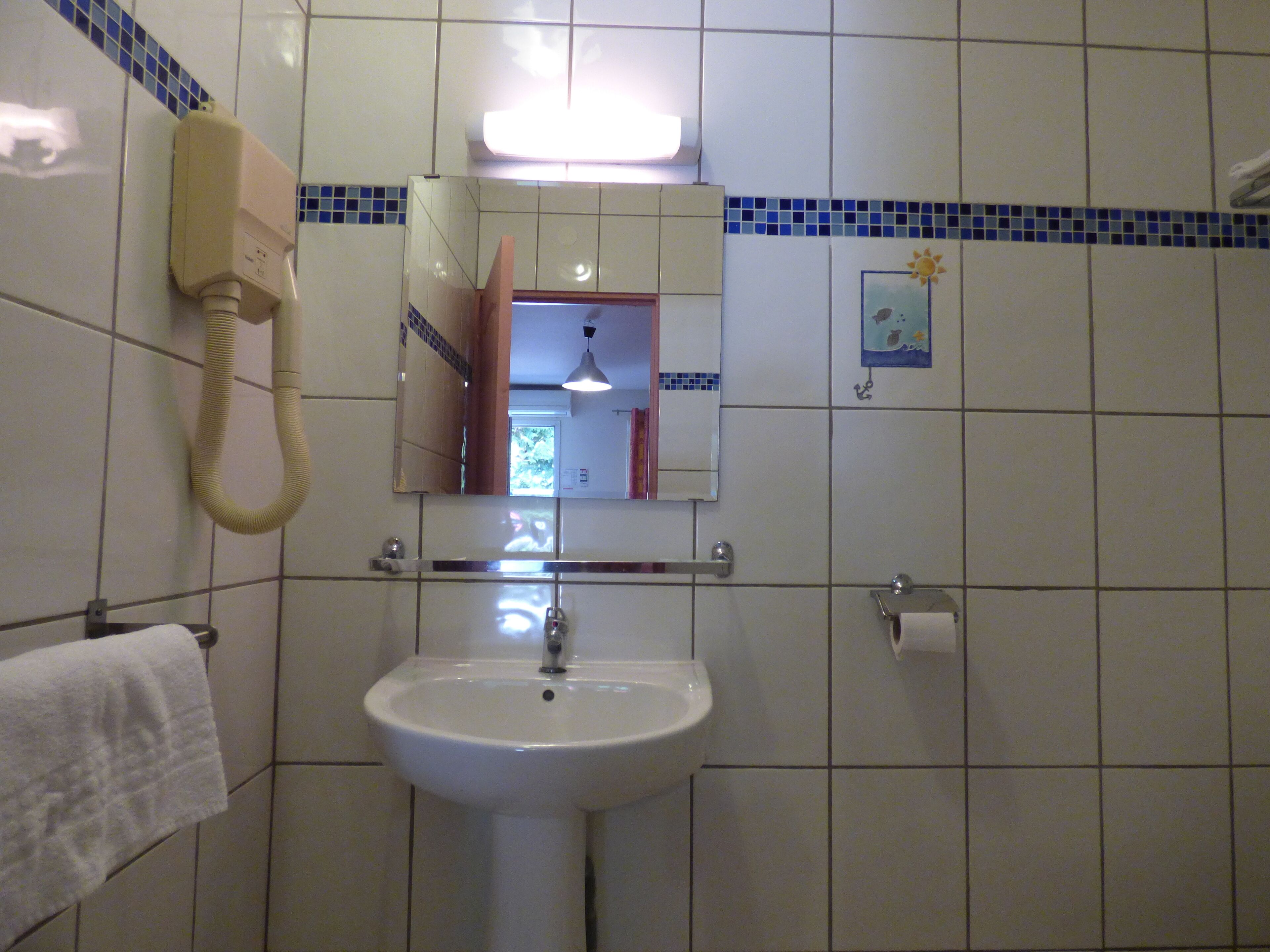 A bathroom with a white sink, a mirror, a telephone, and a towel rack.