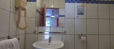 A bathroom with a white sink, a mirror, a telephone, and a towel rack.