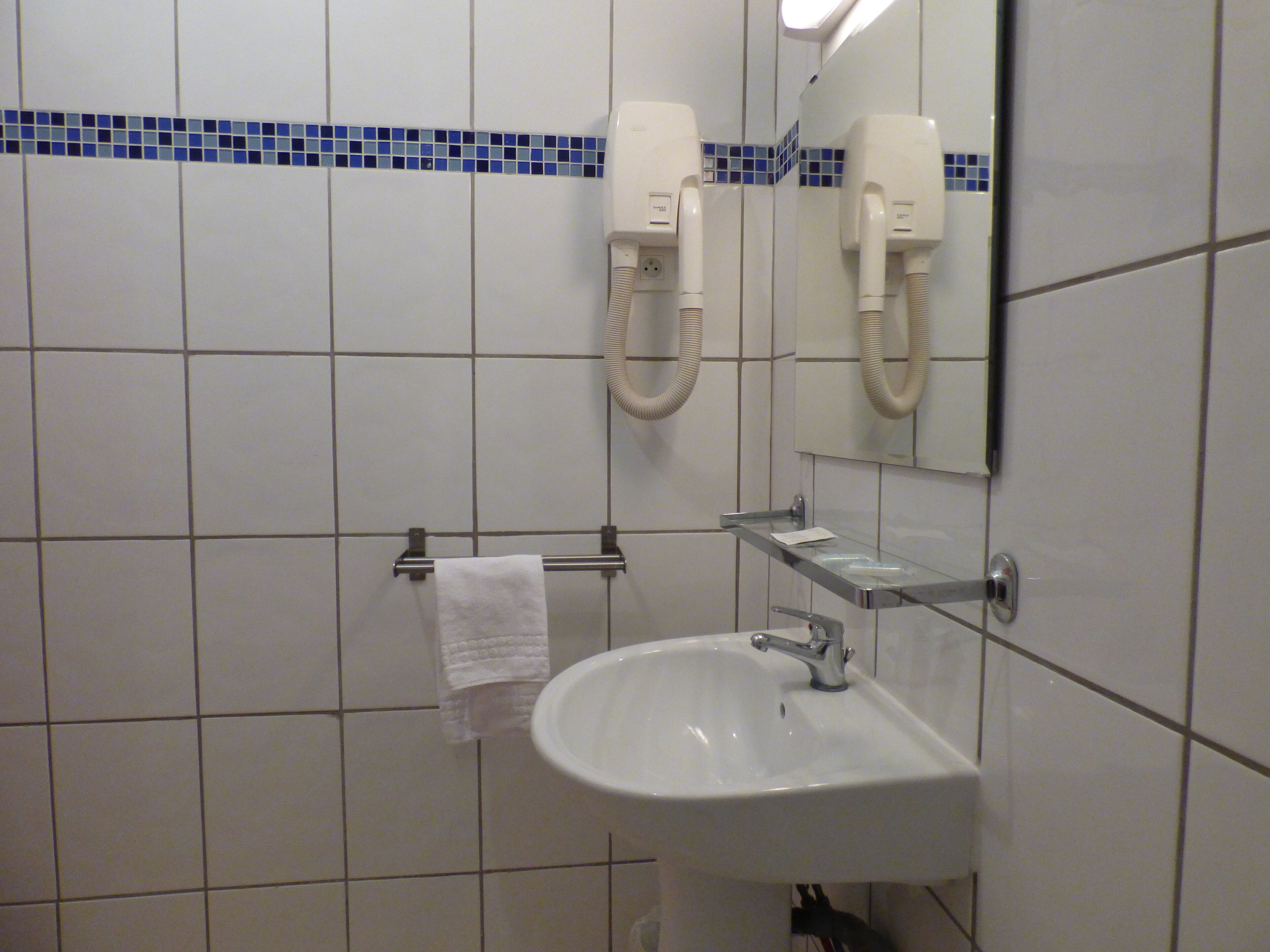 Une salle de bain avec un lavabo blanc, un porte-serviettes et un miroir.