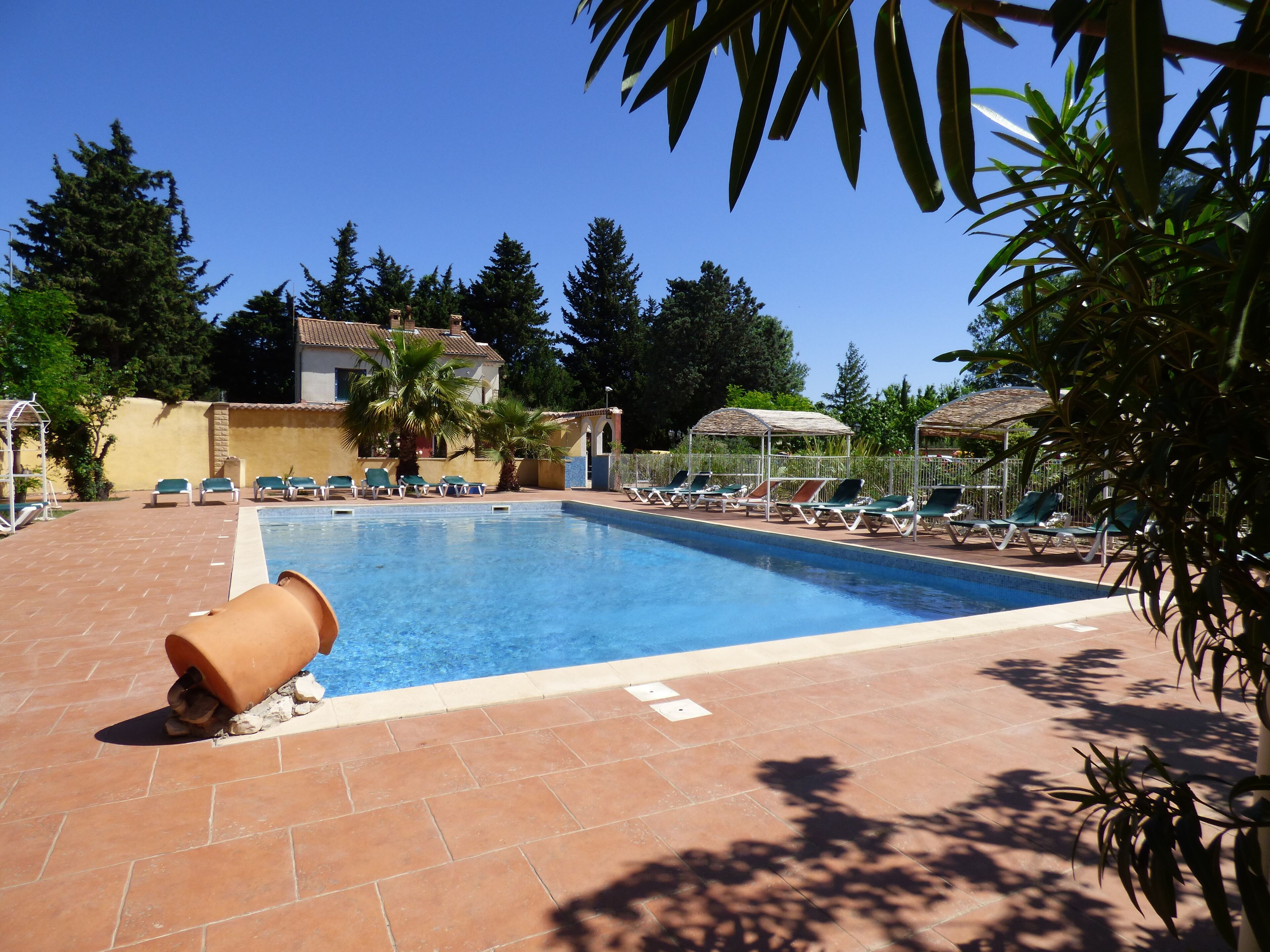 Una piscina con sillas de descanso y un deck con baldosas.