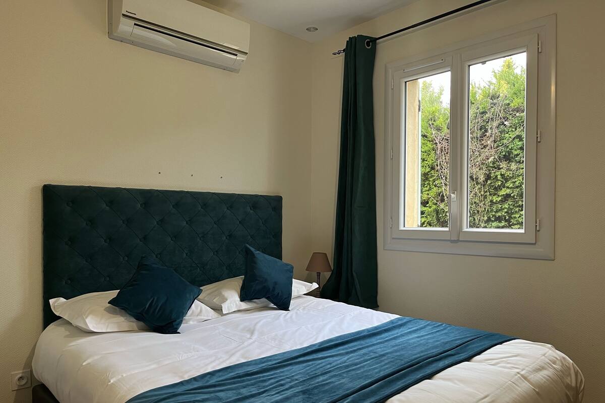A neatly made bed with a dark headboard, white bedding, and a blue throw blanket.