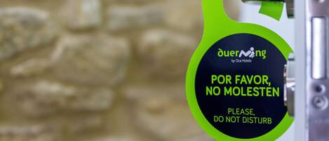 A door sign with the text "OuerMing by Oca Hotels" and "POR FAVOR, NO MOLESTEN PLEASE DO NOT DISTURB".