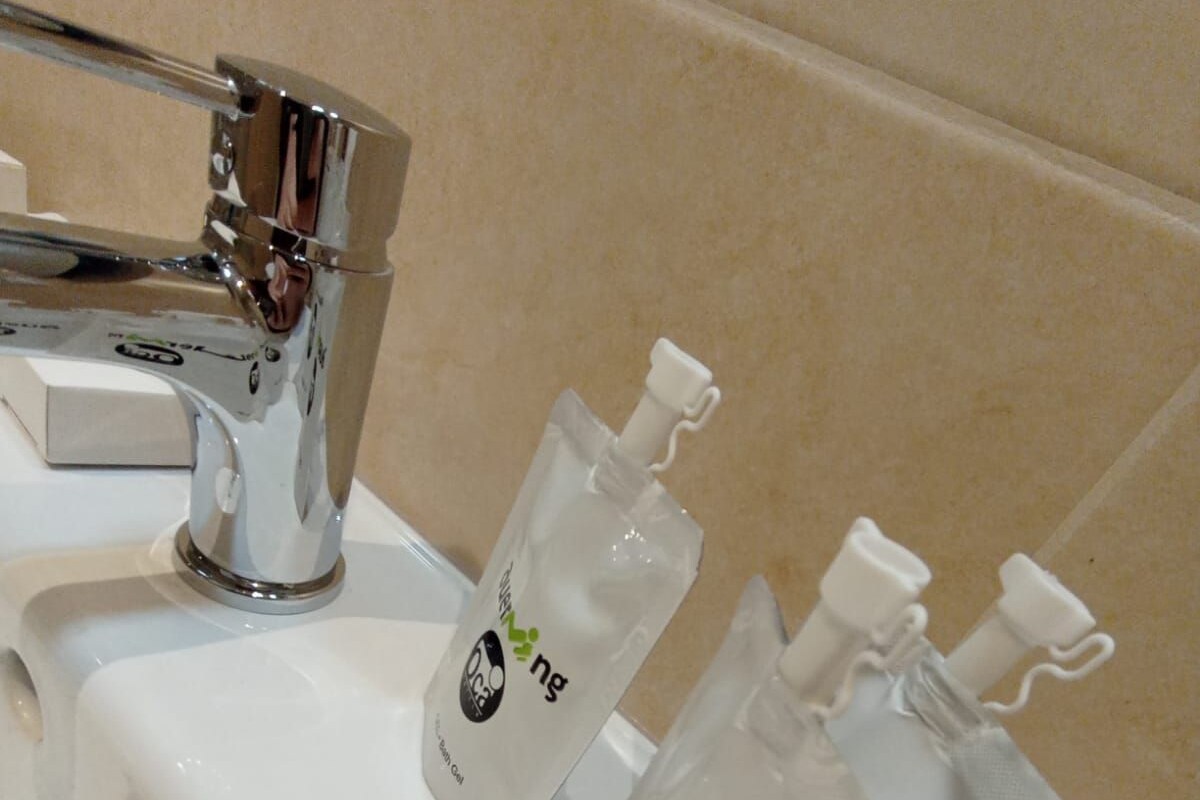 Un lavamanos con tres botellas de gel hidroalcohólico.