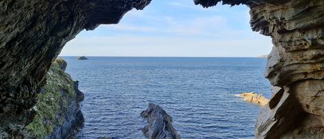 A view through a natural rock arch with the sea and a distant island.