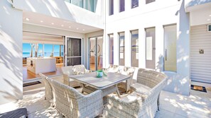 Une vaste terrasse extérieure, dotée de meubles en osier et offrant une vue sur l’océan.