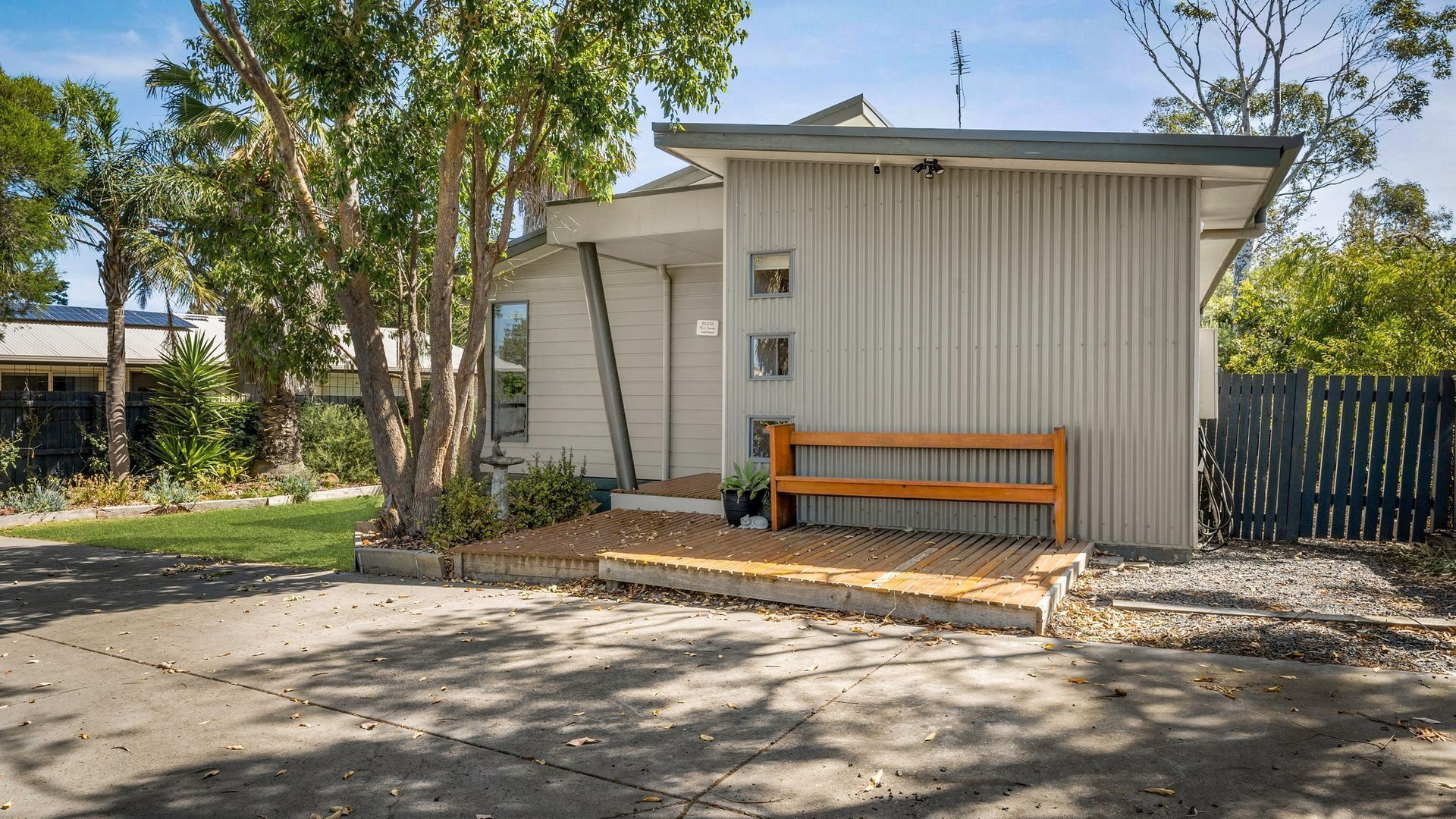 A single-story house with a wooden deck and a bench.