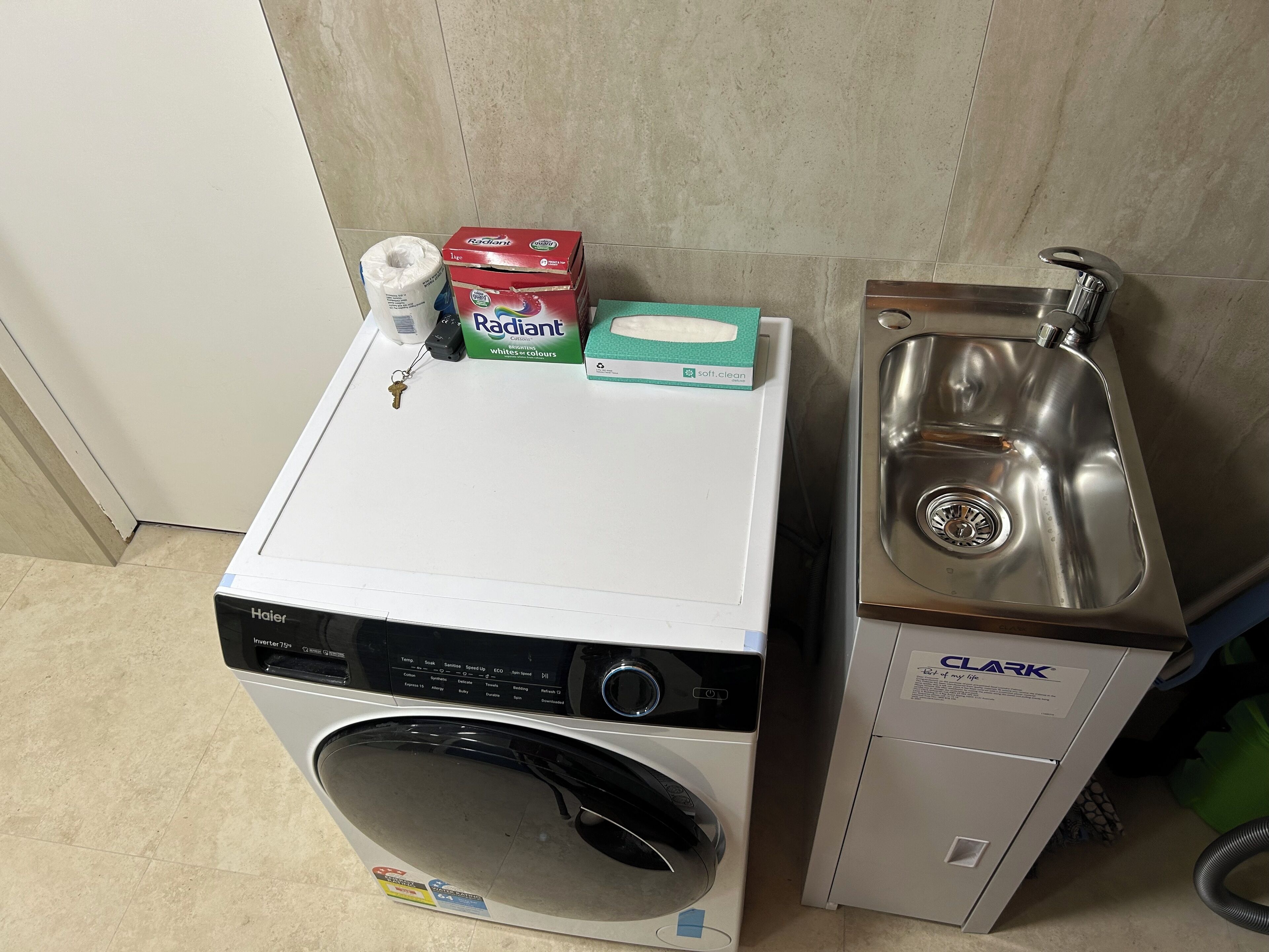 Een kleine keuken met een wasmachine, een spoelbak en een pak keukenpapier.