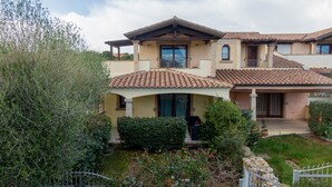 A two-story house with a tiled roof, a covered porch, and a well-maintained garden.