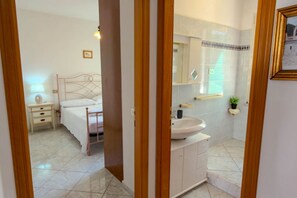 A bedroom with a bed, bedside table, lamp, and a mirror.