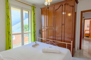 A bedroom with a bed, a wardrobe, and a window with curtains.