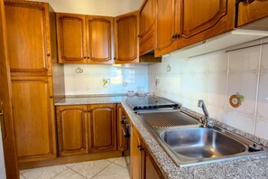 Una cocina con armarios de madera, un lavamanos de acero inoxidable y una estufa integrada.