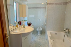 Un baño con lavamanos, espejo, bidé y bañera.