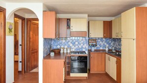 A compact kitchen with wooden cabinets, a built-in oven, and a tiled backsplash.