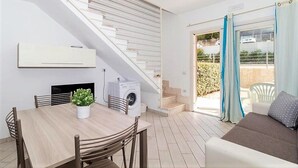 A modern apartment with a dining area, a washing machine, a staircase, and a sofa by a sliding glass door. - Affittimoderni Viddalba Sea Stars - VISM11 (Viddalba)