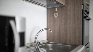 A modern kitchen with a stainless steel sink, a heart-shaped wall decoration, and a built-in oven. - Affittimoderni Viddalba Sea Stars - VISM11 (Viddalba)