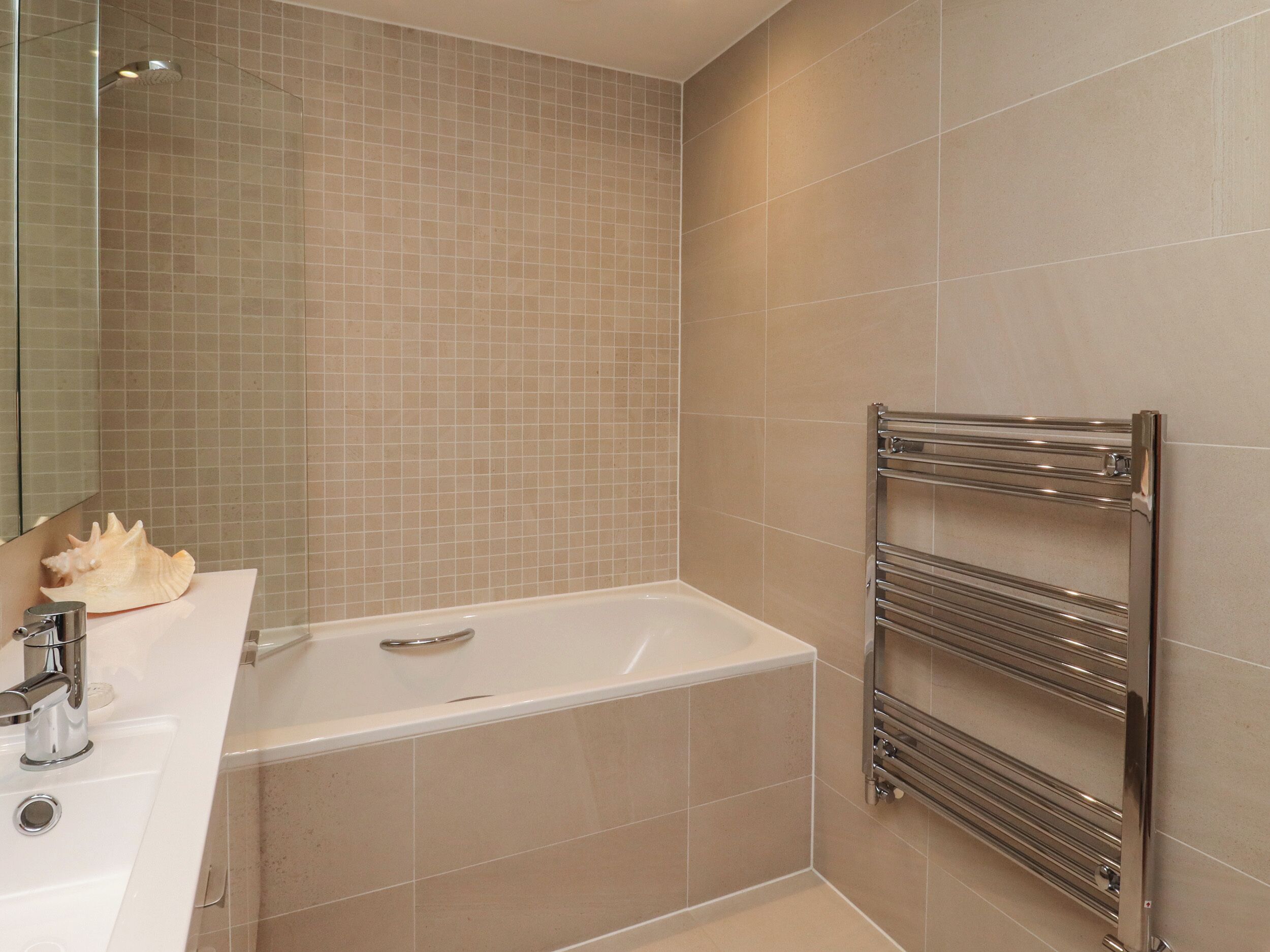A modern bathroom with a bathtub, a sink, and a towel rack.
