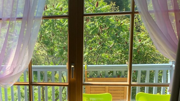 Una stanza con vista su un balcone, un tavolo e una sedia.