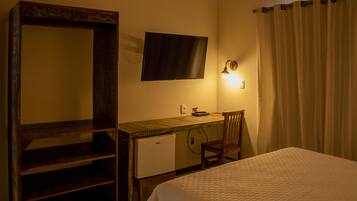 Une chambre comprenant un lit, un bureau, une chaise, un téléviseur et un petit réfrigérateur.