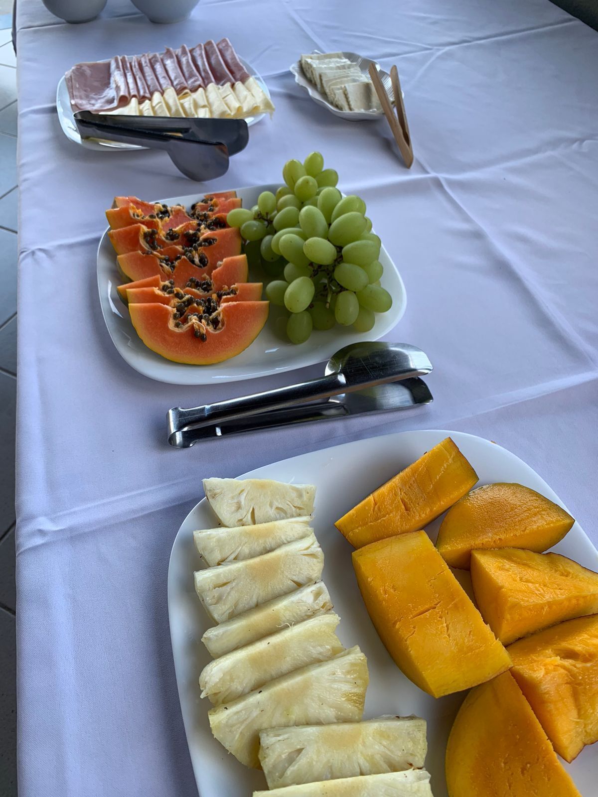 Una mesa con diversas frutas y aperitivos, como papaya, uvas y rodajas de piña.