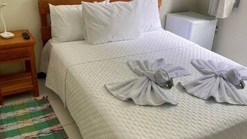 A neatly made bed with white bedding and towels arranged on the bed.