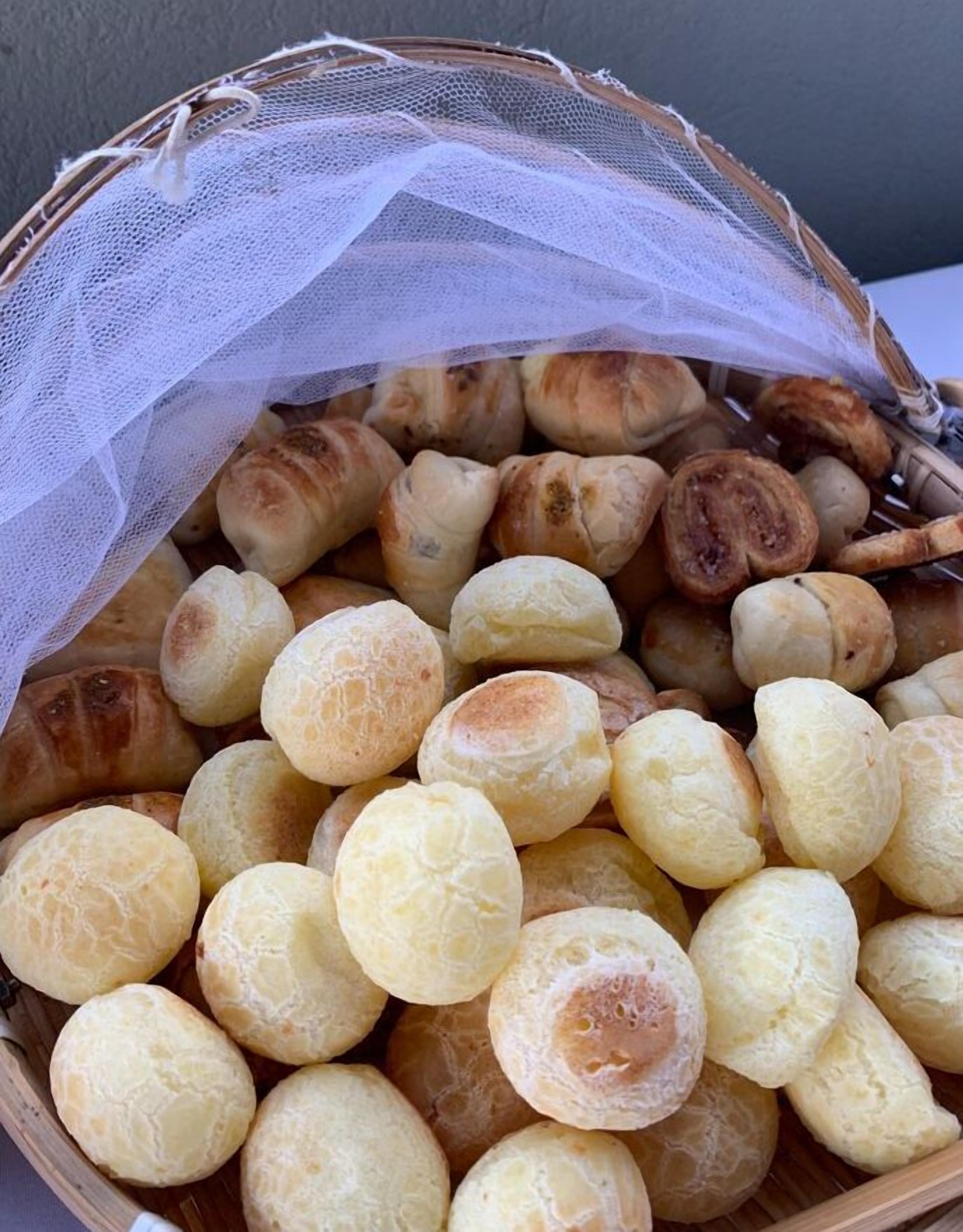 A basket filled with small, round, golden-brown pastries, likely a type of bread or pastry, covered with a white mesh.