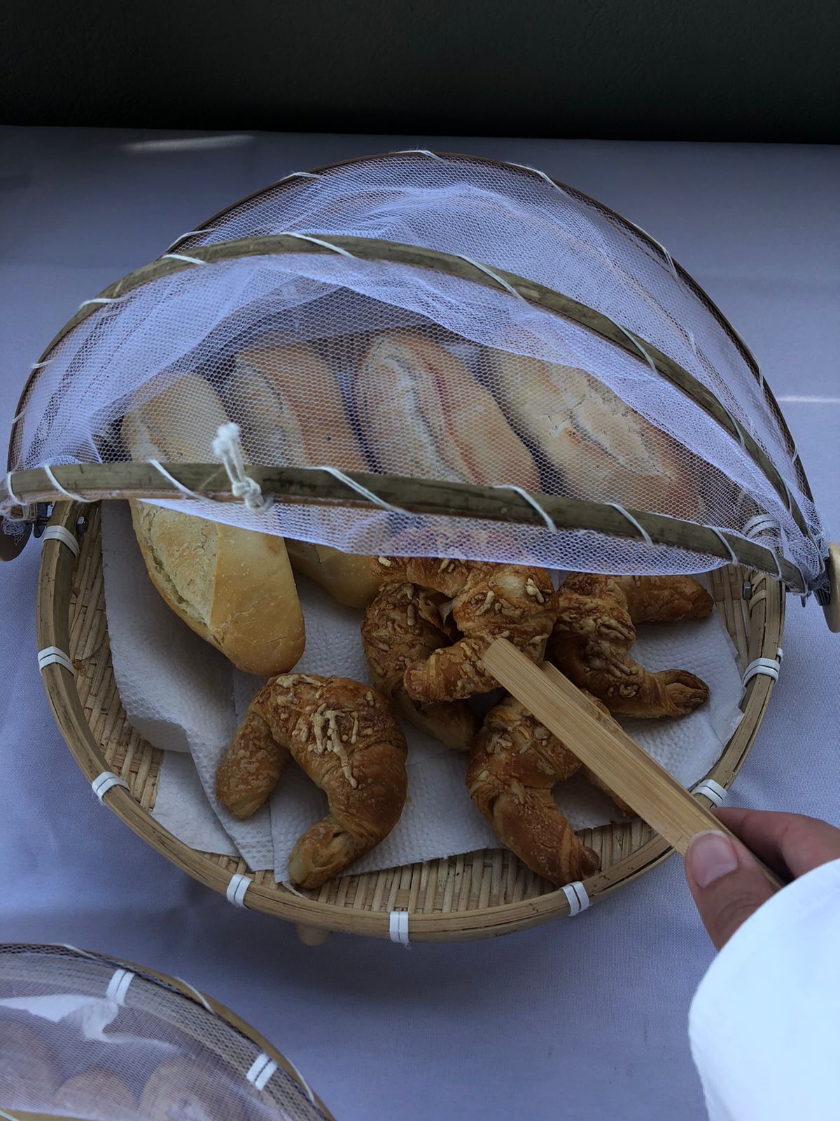 Una cesta con tapa de malla que contiene pan y pasteles.