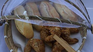 Una cesta con tapa de malla que contiene pan y pasteles.