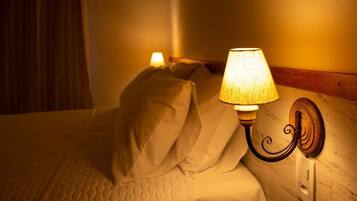 A bed with a quilted cover and a wall-mounted lamp.