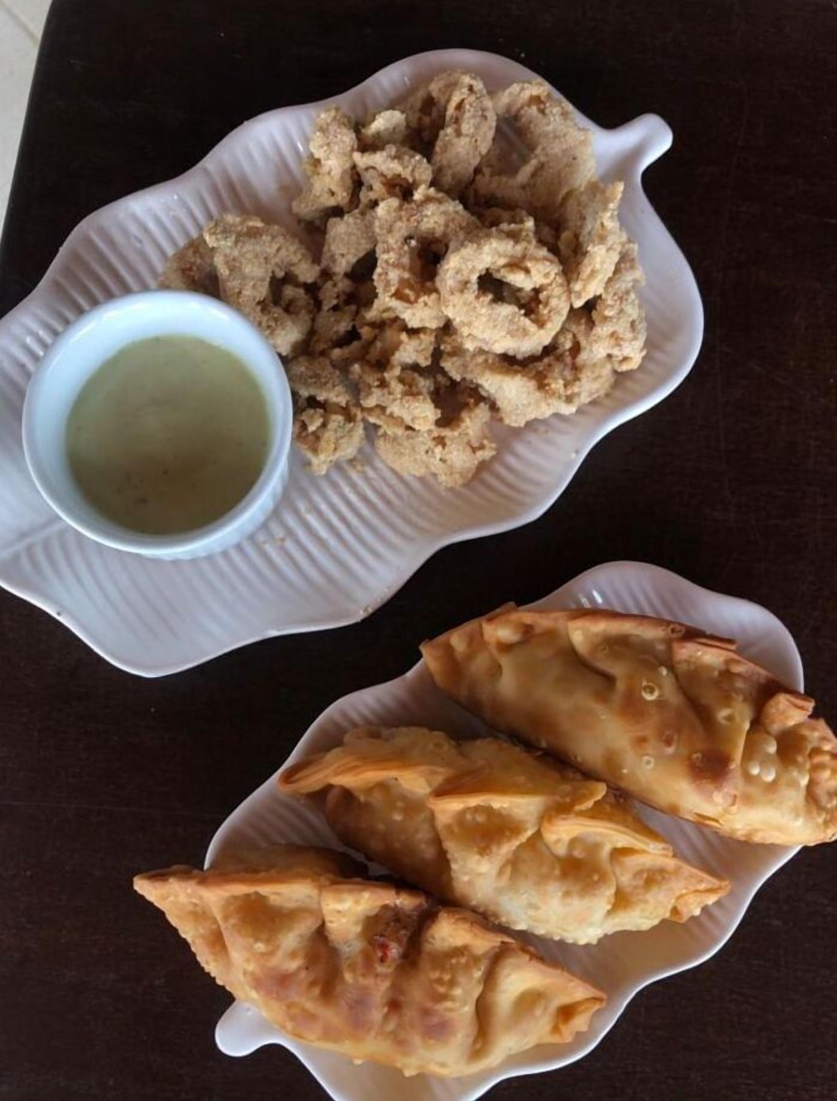 A plate of fried snacks and a bowl of dipping sauce.